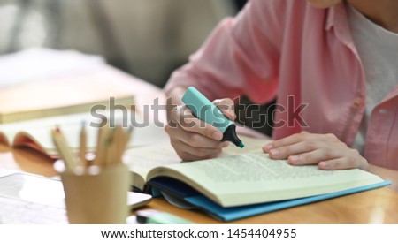 Cropped shot young female using highlight pen on book with education lesson concept. Royalty-Free Stock Photo #1454404955