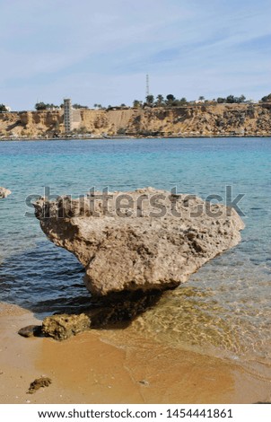 Big stone on the beach, yellow sand, in the distance a mountain with towers Royalty-Free Stock Photo #1454441861