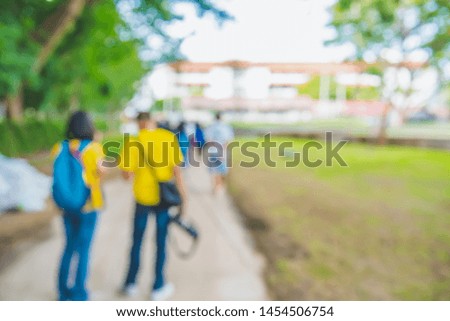 Abstract blur image of people walking in green garden with bokeh for background usage . (vintage tone)