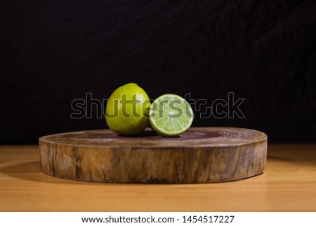 
Green lemon on black background on top of wooden table