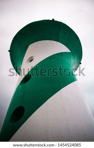 
A green and white lighthouse in the middle of nowhere on a rainy day.