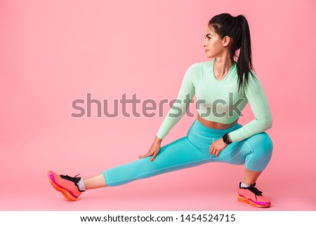 Picture of beautiful young sports fitness woman isolated over pink wall background make stretching exercises.