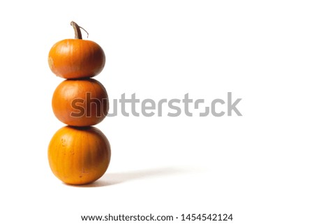 Tower of orange pumpkins standing one on other on white background, front view