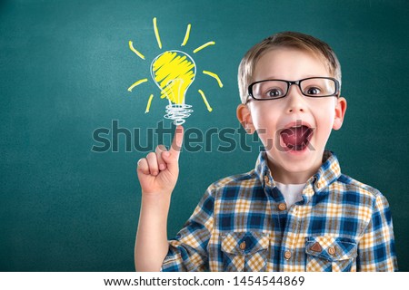 Portrait of male elementary school student with lightbulb picture on blackboard Royalty-Free Stock Photo #1454544869