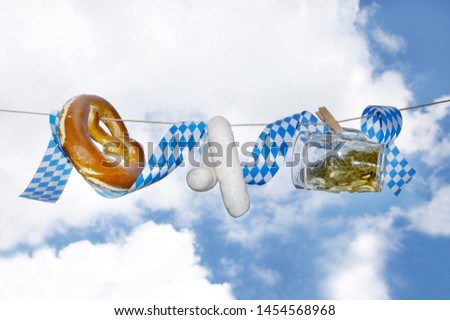 Beer, pretzel and white sausages are hanging before sky, copy space