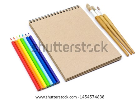 Watercolour brushes, Coloured pencils, notebook isolated on white background for mockup. Flat lay, top view. Concept: Back to school.