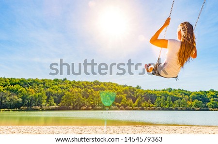 Woman on a swing at a lake with sandy beach