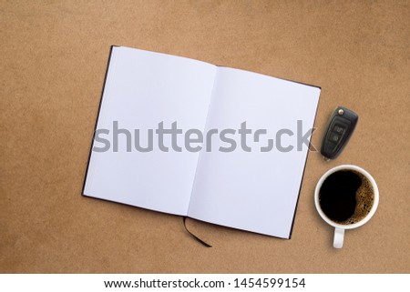 Blank notepad or notebook and coffee cup on brown wood table background.using wallpaper for education, business photo.Take note of the product for book with paper and concept,Diary on brown wood table