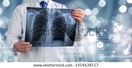 A young doctor is standing backside and examining the lungs image with total medical system structure at the foreground. The concept of medical service, diagnosis and treatment.
    
    - Image