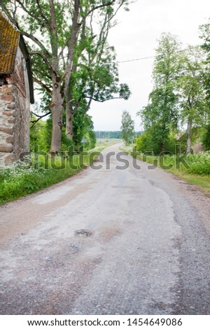 Countryside road with trees and old home corner