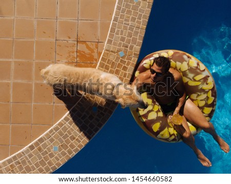 from above a man on beach mat in swimming pool of a villa house in a sunny day