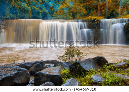 Photograph of beautiful waterfall with colorful trees in Thailand.