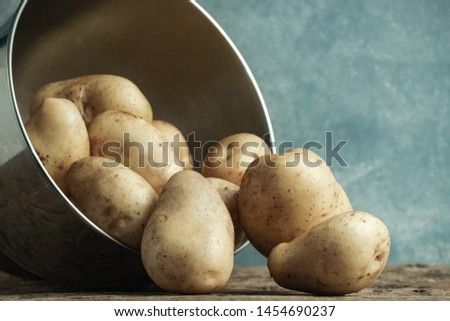 Close up Fresh potato in silver bowl on a old oak wooden table and beautiful gray wall background.