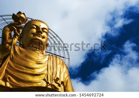 The golden buddha statue of Van Hanh pagoda under the deep blue sky and fluffy white clouds. Outdoor picture taken on a sunny spring day in Dalat, Vietnam.