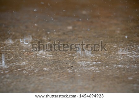 Blurred raining droplets falling on ground cement background