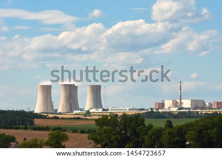 View of smoking chimneys of nuclear power plant, power lines and forest, under blue sky with white clouds Royalty-Free Stock Photo #1454723657