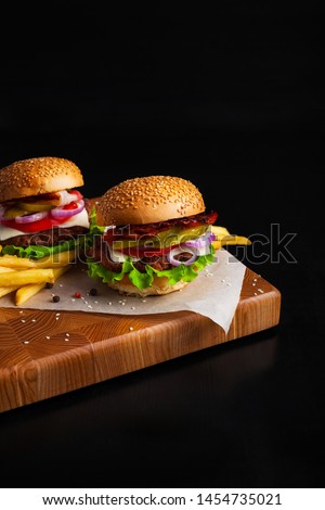 Beef burgers on a board with fries on a black background