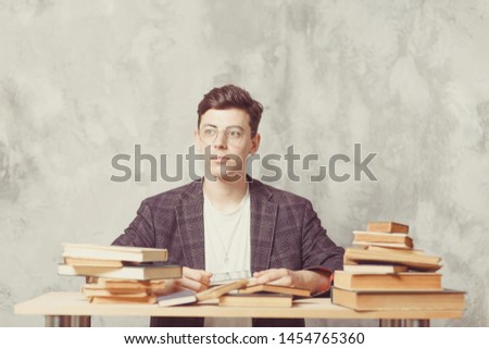 Young boy student sitting near the table with books in glasses. happy guy want learning, have education. online education. Study in school. Male thinking. Electronic library, e-book concept