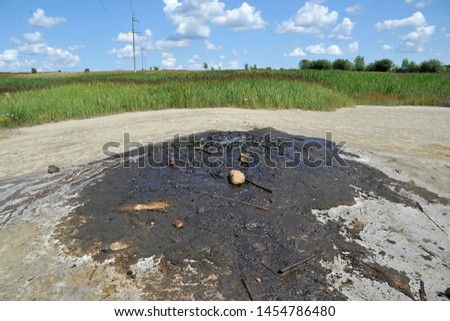 Active mud (clay and bitumen) volcano on the outskirts of the village Starunja in Carpathian. Spills of crude oil on the soil surface. Crater of the mud volcano. 