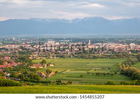 Panorama of the Transylvanian town of Fagaras and its surrounding countryside, against a backdrop of a snowcapped Carpathian mountain range. Fagaras, Brasov County, Transylvania, Romania