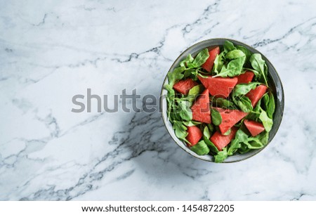 Fresh summer watermelon salad with arugula, spinach and greens on light marble background. Healthy food, clean eating, Buddha bowl salad, top view