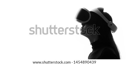 Beautiful woman over white light background. Girl in glasses of virtual reality. Augmented reality, game, hobby concept. VR. Black and white.