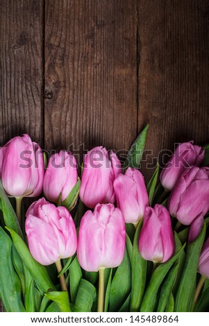 Pink tulips over old  wooden table as a background
