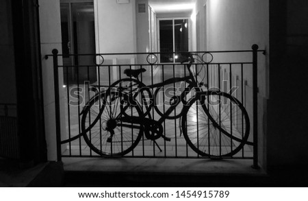 Vintage style photo of a bike against a railing in the entrance to an empty building, in black and white