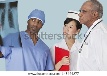 Multi ethnic doctors examining x-ray report over light blue background