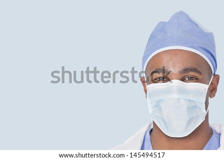 Close-up of a male doctor wearing facemask over light blue background