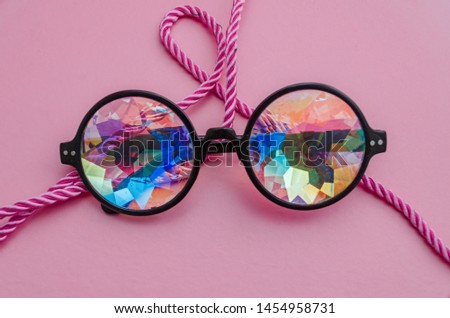 Designer glasses with kaleidoscope lenses with a rope on a pink background