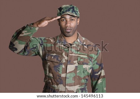 Portrait of a young African American US Marine Corps soldier saluting over brown background