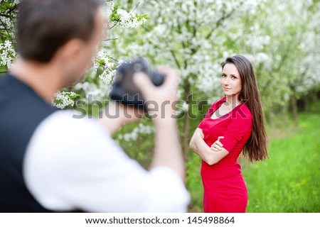 Photographer is taking photos of beautiful woman in red dress in nature