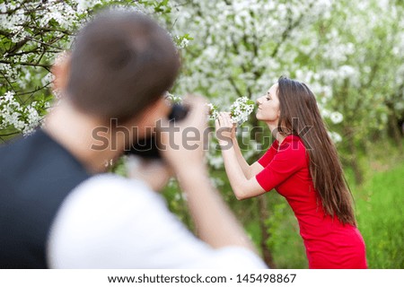 Photographer is taking photos of beautiful woman in red dress in nature