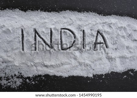 the word "India" is written in salt on a black board