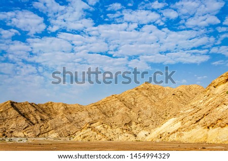 Orange Mountain range on a plateau with beautiful clouds as background. From Muscat, Oman.