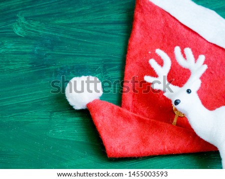 christmas deer on green background ith copy space and red santa hat