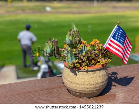 Patriotic flower pot with American flags and golfer on the background.  American flag decoration.