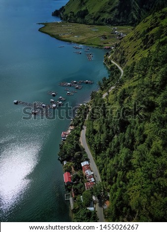 Panoramic views of the lake with trees on a hill and asphalt road (Takengon, Aceh, Indonesia) 