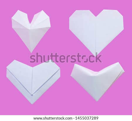 White paper folded origami into various heart shapes isolated on pink background.