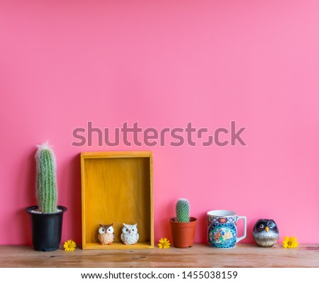 Beautiful  cactus,wooden  shelf,cup  and  simulated  owl  on  wood  table  with  pink  background