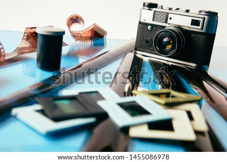 old camera and old used film on a blue mirror background