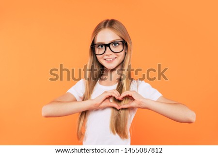 Close up portrait of happy, funny and beautiful blonde little girl in glasses is posing over yellow background. Study, education, school, university, college, graduate concept.