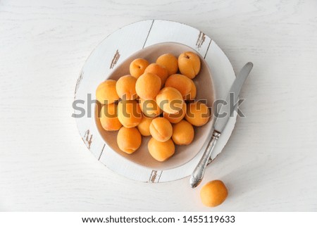 Plate with tasty ripe apricots on white wooden table