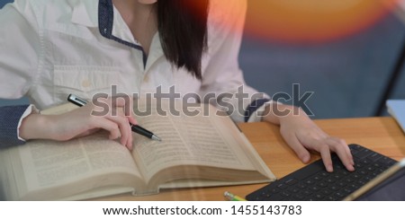 Close-up of female student studying at college library while using laptop computer with blurred background 