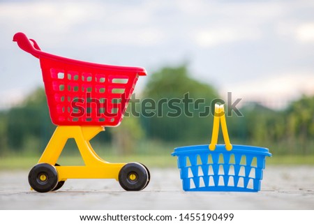 Bright plastic colorful toys, shopping cart and basket outdoors on sunny summer day.