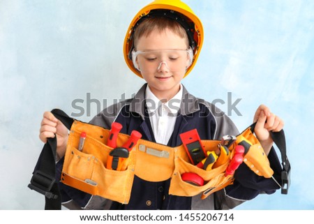 Cute little boy with tools belt on color background
