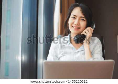Happy asian business woman talking the phone at the working place.