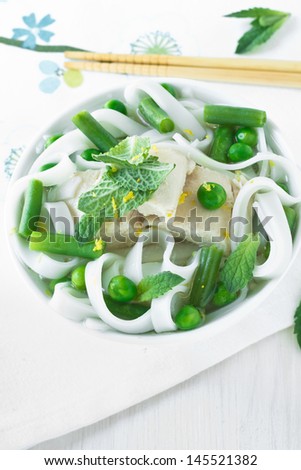 Chicken and peas laksa topped with mint leaves in white bowl