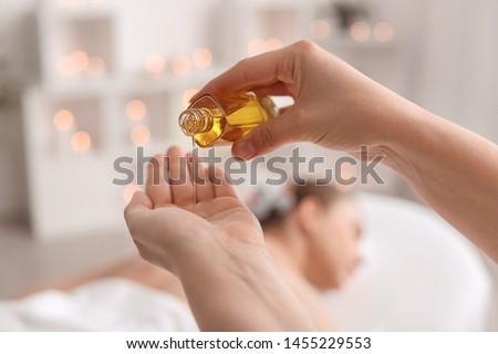 Massage therapist pouring essential oil onto hand in spa salon Royalty-Free Stock Photo #1455229553